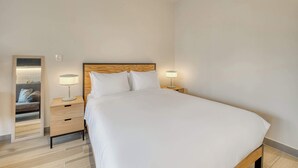 A hotel room with a large bed, two bedside tables with lamps, a wooden headboard, and a mirror on the left wall. - Providencia Deluxe Studio in Brand-New Building (Guadalajara)