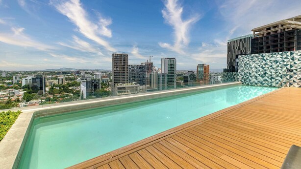 A rooftop pool with a clear view of the city skyline, including several high-rise buildings and a construction crane. - Providencia Deluxe Studio in Brand-New Building (Guadalajara)