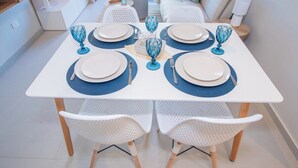 A dining table set with plates, cutlery, and blue glassware, surrounded by white chairs in a modern interior. - Walk to Malls 200Mbps Pool, Gym & BBQ (Asunción)