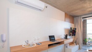 A modern room with a wooden desk, a laptop, a flat-screen TV, and a small seating area. - Walk to Malls 200Mbps Pool, Gym & BBQ (Asunción)