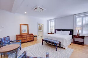 Ein Schlafzimmer mit einem Bett, einem Holzschrank, einem Stuhl, einer Bank und einem Nachttisch.