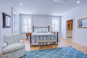 A bedroom with a bed, a chair, a bedside table, and a window. - Exclusive Property Just Steps from History & Culture (Charleston)