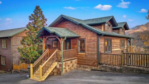A wooden cabin with a porch, a staircase, and a stone foundation. - Killer View|Amazing Pool|2 mi Gburg|Game Rm|Modern (Gatlinburg)