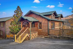 A wooden cabin with a porch, a staircase, and a stone foundation. - Killer View|Amazing Pool|2 mi Gburg|Game Rm|Modern (Gatlinburg)