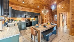 A modern kitchen with dark cabinets, stainless steel appliances, and a central island with seating. - Killer View|Amazing Pool|2 mi Gburg|Game Rm|Modern (Gatlinburg)