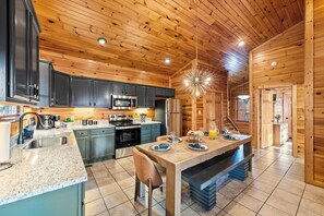 A modern kitchen with dark cabinets, stainless steel appliances, and a central island with seating. - Killer View|Amazing Pool|2 mi Gburg|Game Rm|Modern (Gatlinburg)
