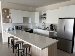 A modern kitchen with a central island, stainless steel appliances, and bar stools. - New Luxury Apartment - Terrazas San Carlos (San Carlos)