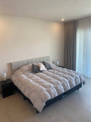 Ein modernes Schlafzimmer mit einem großen Bett, einem Nachttisch und einem Beistelltisch.