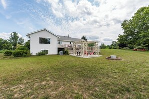 A single-story house with a covered patio area and a fire pit in the yard. - Acres Away - 50 Acre Farmland, Family Retreat, Private Yard (Fennville)
