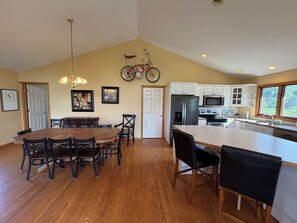 A kitchen with wooden flooring, white cabinets, a stainless steel refrigerator, and a bicycle mounted on the wall. - Acres Away - 50 Acre Farmland, Family Retreat, Private Yard (Fennville)