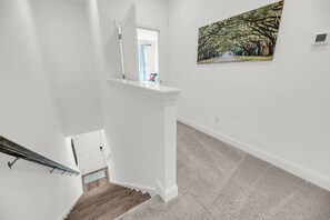 Eine Treppe mit Handlauf, eine weiße Wand und ein Bild von einem Baumweg.
