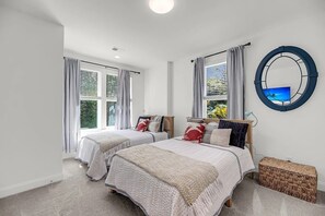 Ein Schlafzimmer mit zwei Betten, einem großen Spiegel und Blick auf Grünflächen.