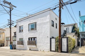 A white building with a garage door, a small window, and a utility pole with wires. - Sunlit Venice Escape — Walk to Beach in Seconds (Los Angeles)