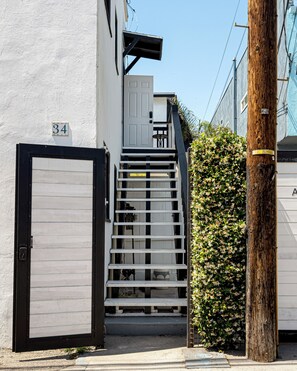 A residential building with a white exterior, a black gate, and a staircase leading to a door marked with the number 34. - Cozy 1-bedroom apartment in beautiful Venice Beach with AC (Los Angeles)