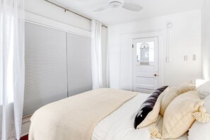 A bedroom with a bed, a ceiling fan, a door, and a window with blinds. - Cozy 1-bedroom apartment in beautiful Venice Beach with AC (Los Angeles)