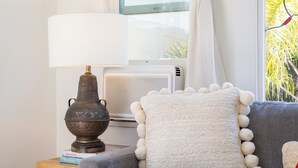 Ett modernt vardagsrum med en grå soffa, en vit lampa och en dekorativ skål på ett litet bord i trä.