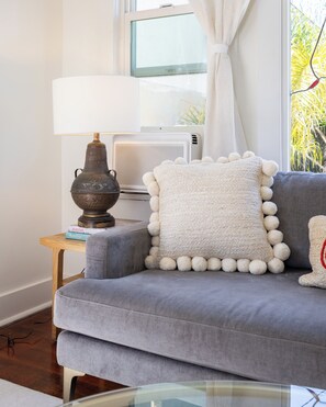 A modern living room with a grey sofa, a white lamp, and a decorative bowl on a wooden side table. - Cozy 1-bedroom apartment in beautiful Venice Beach with AC (Los Angeles)