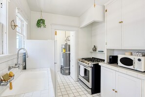 A kitchen with white cabinets, a stainless steel sink, a stove, and a microwave. - Cozy 1-bedroom apartment in beautiful Venice Beach with AC (Los Angeles)