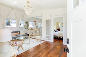 A modern living room with a sofa, a glass coffee table, and a chandelier. - Cozy 1-bedroom apartment in beautiful Venice Beach with AC (Los Angeles)
