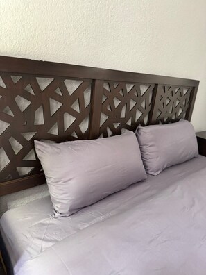 A bed with a headboard featuring a geometric pattern, accompanied by two pillows. - Amplio Oasis con Balcón en Roma Norte (Mexico City)