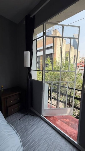 Ein Zimmer mit einem großen Fenster, einem Holzkasten und einer Lampe.