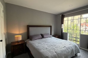Ein Schlafzimmer mit einem Bett, Nachttischen, einer Lampe und einem Fenster mit Blick.