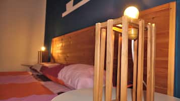 Een houten bed met een witte matras en een nachtkastje met een lamp.