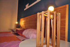 Ein Bett mit Holzrahmen, einer weißen Matratze und einem Nachttisch mit Lampe.