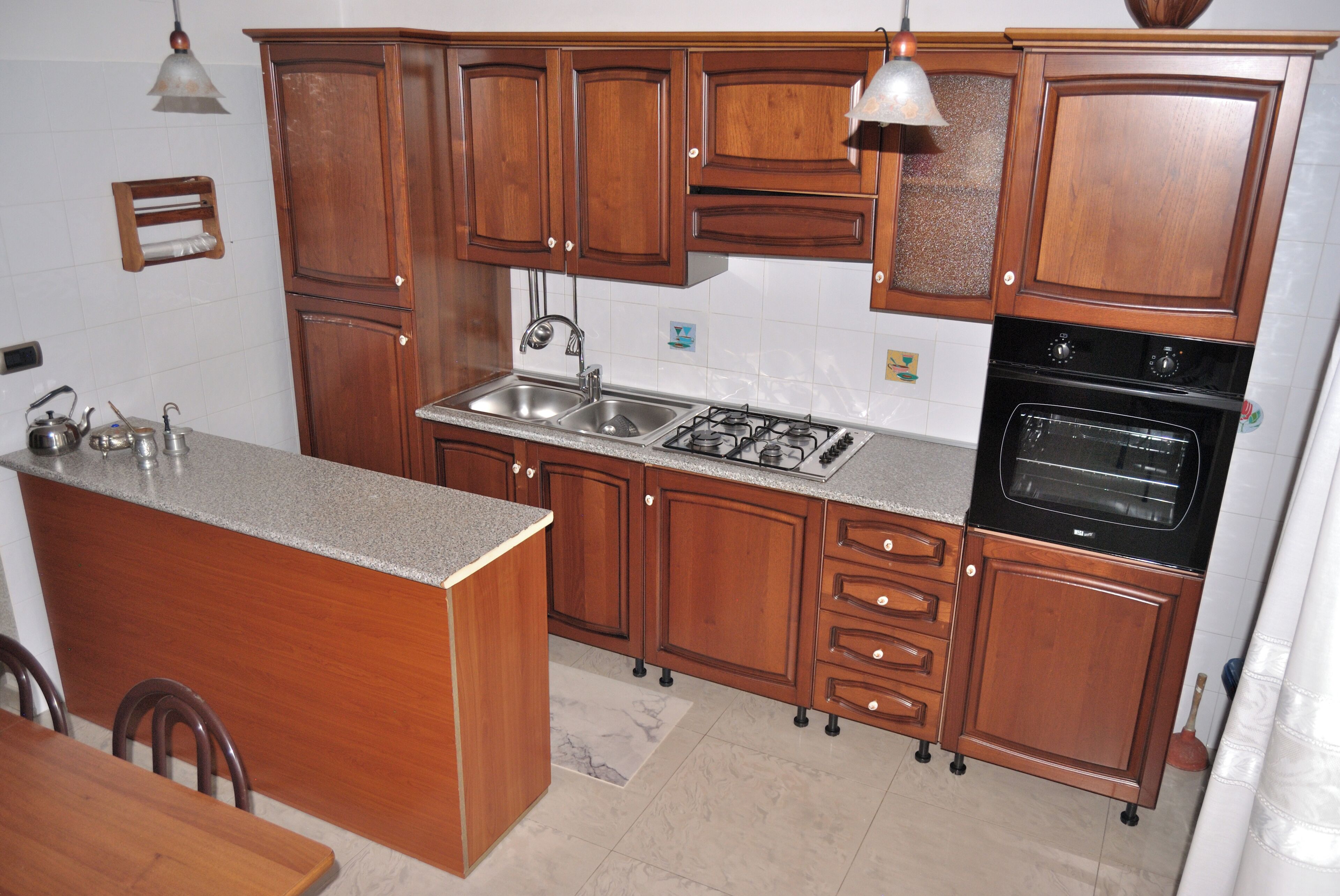 Eine Küche mit Holzschränken, einer Granit Arbeitsplatte, einer Spüle, einem Herd und einem Backofen.