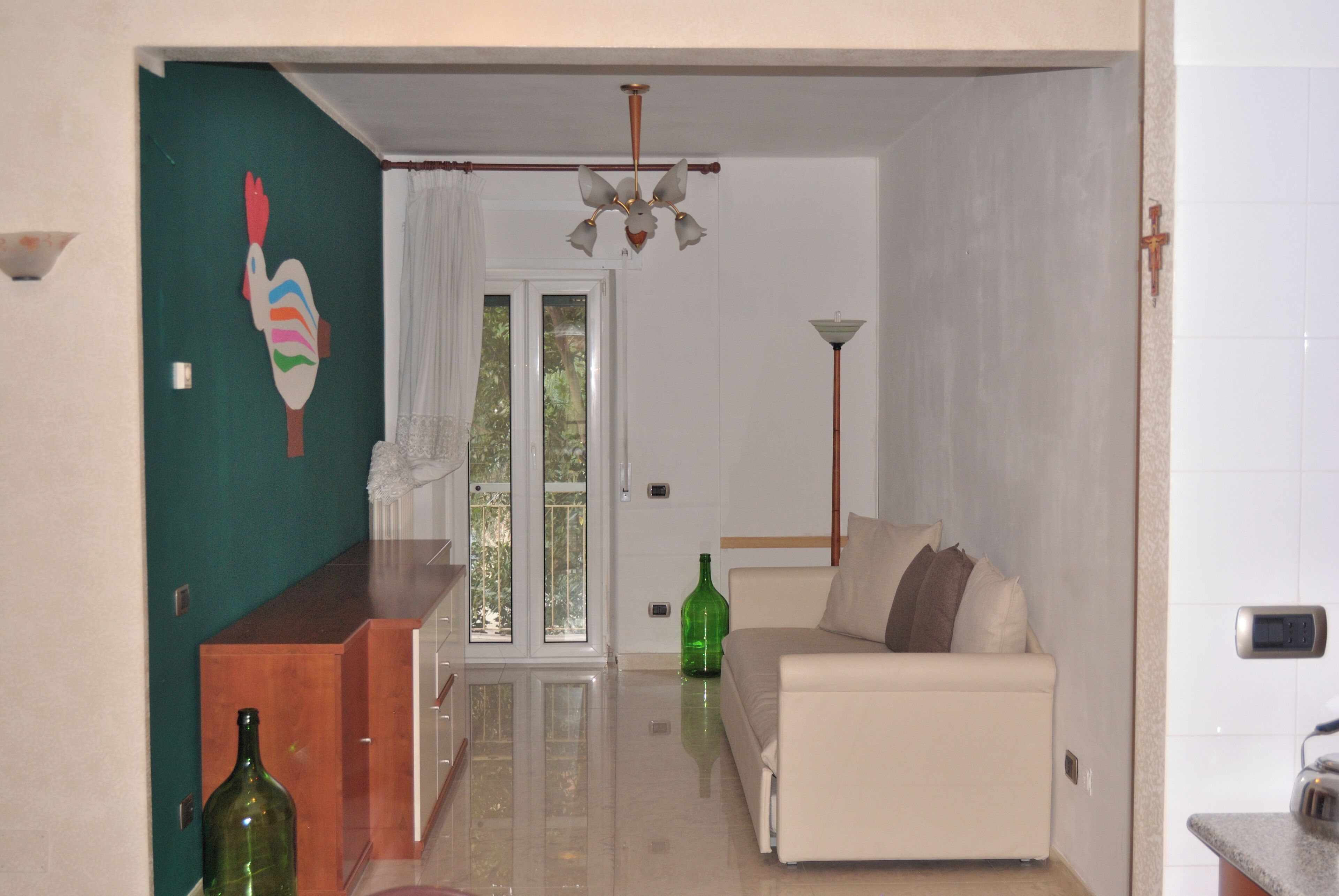 A living room with a sofa, a wooden side table, a green bottle, and a painting on the wall.