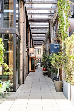 A narrow pedestrian walkway with glass-fronted shops, outdoor seating, and potted plants. - Roomy apartment in Capitol Hill Seattle (Seattle)