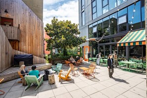 An outdoor seating area with tables and chairs, a wooden wall, and a building with large windows. - Roomy apartment in Capitol Hill Seattle (Seattle)