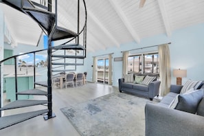 A spacious living area with a spiral staircase, a gray sofa set, and a view through large windows. - Isla Bella - 3BR, Private Pool, Near SP Beach (South Padre Island)