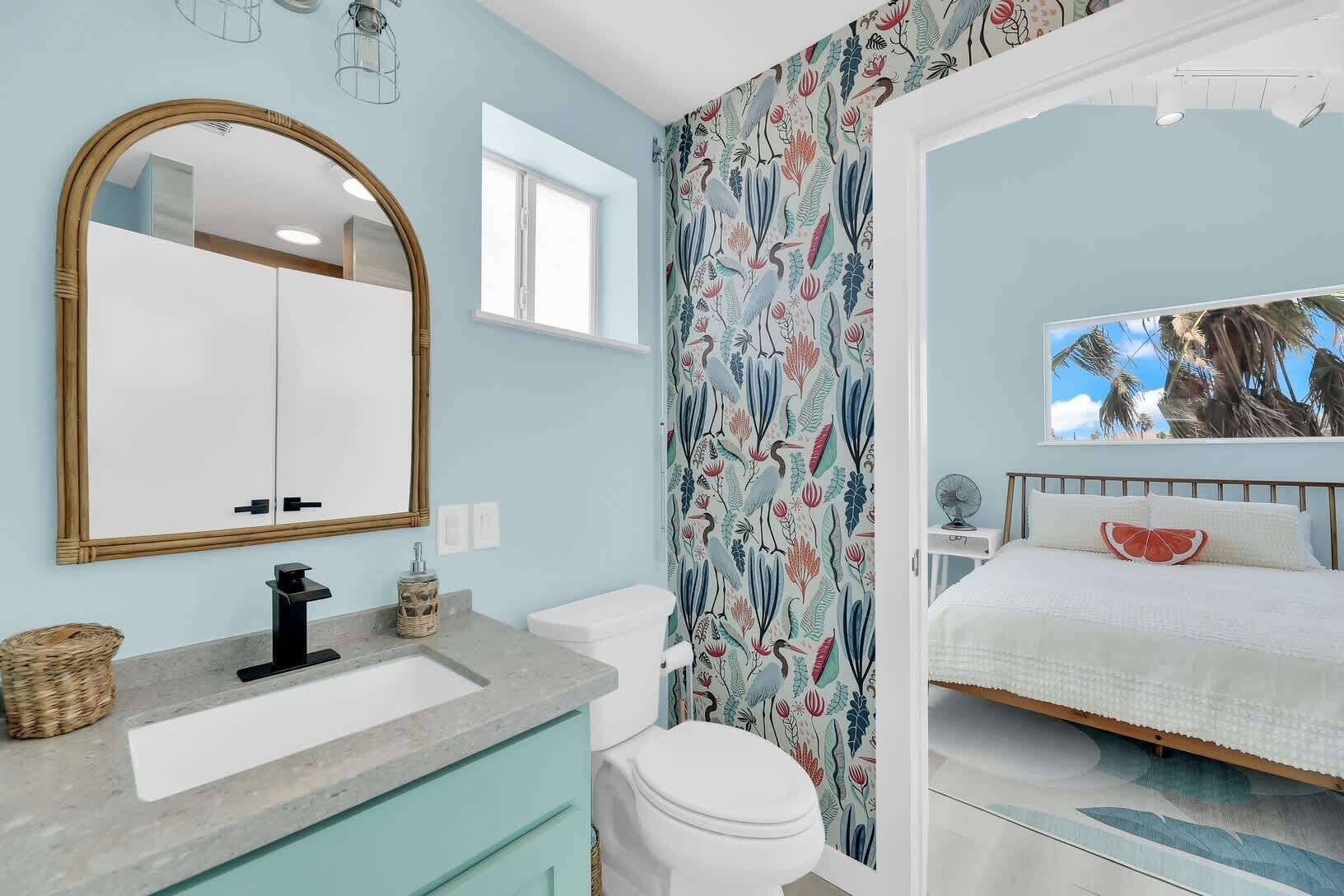 A bathroom with a large mirror, a sink, and a toilet.