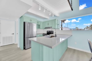 A modern kitchen with a large island, stainless steel appliances, and light green cabinetry. - Isla Bella - 3BR, Private Pool, Near SP Beach (South Padre Island)
