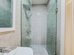A modern bathroom with a glass-enclosed shower, a white sink, and marble tiles. - Exclusive Studio Apartment in Victoria Island with Pool, Fast Wi-Fi & 24/7 Power (Lagos)