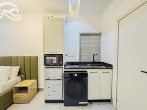 A compact kitchenette with a microwave, dishwasher, and a small sink. - Exclusive Studio Apartment in Victoria Island with Pool, Fast Wi-Fi & 24/7 Power (Lagos)