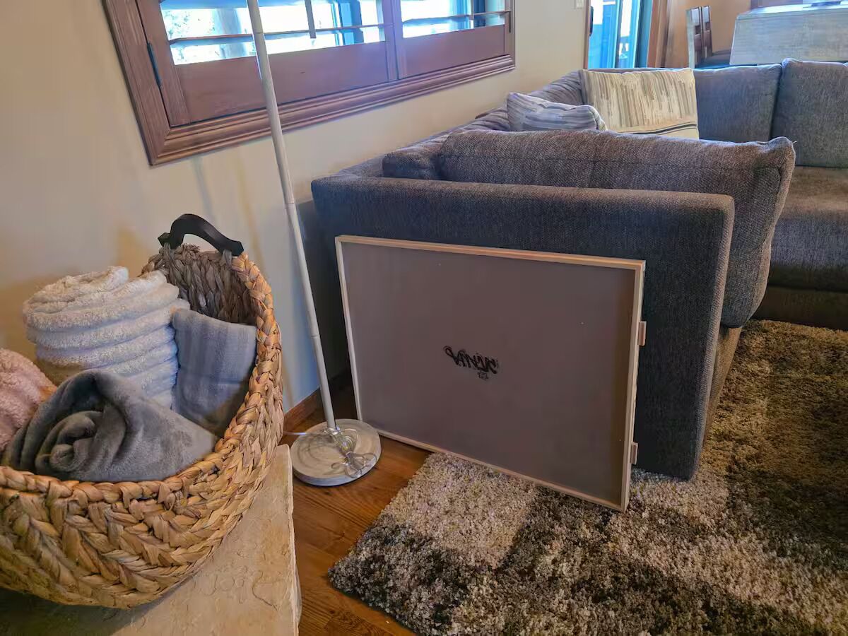 A living room with a grey sofa, a wicker basket with towels, and a floor lamp.