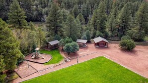 An aerial view of a property with a playground, a covered picnic area, and a building with a red roof.