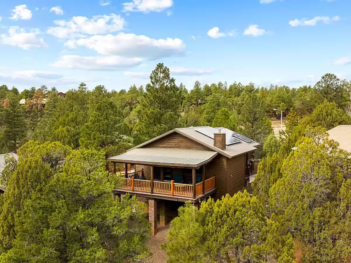 Une cabane en bois dotée d’un balcon, entourée d’une forêt dense.