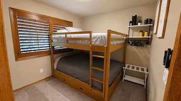 A bunk bed room with a window, a shelf with plants, and a door.
