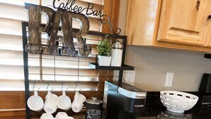 Una cucina con angolo caffè, dotato di macchina da caffè, tazze e un cartello con la scritta 'Coffee Bar'.