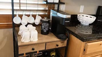 Une cuisine équipée d’un coin café comprenant une machine à café, des tasses et un panneau indiquant « Bar à café ».