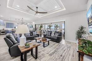 Un salon spacieux doté d’un ventilateur de plafond, d’une cheminée et offrant une vue sur l’océan.