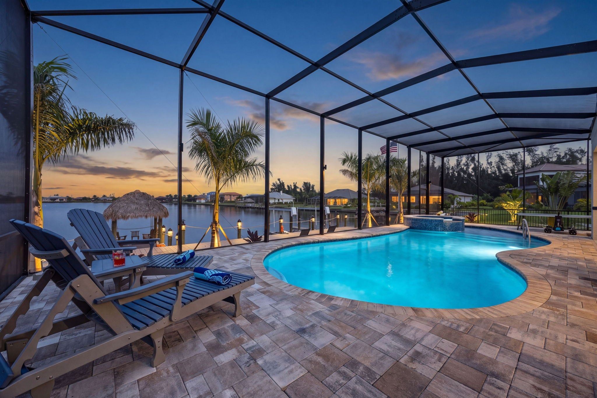 A pool area with lounge chairs and a view of the water.