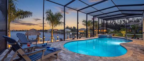 A pool area with lounge chairs and a view of the water.