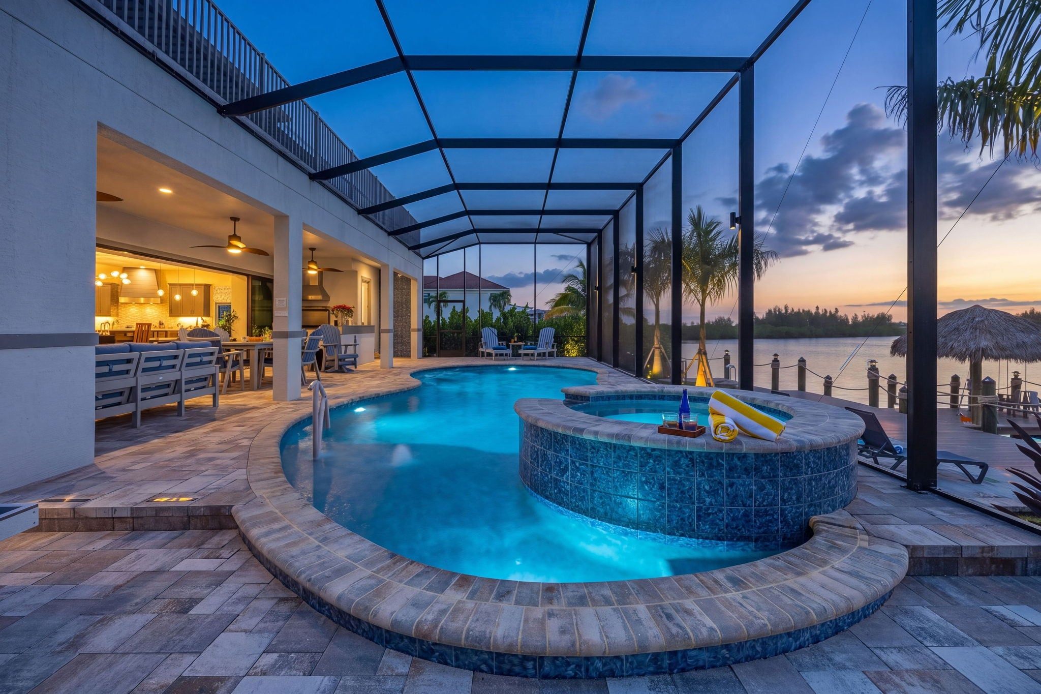 A swimming pool with a hot tub, outdoor seating, and a view of the water.