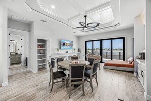 A modern kitchen with a dining area, a large window with a view, and a ceiling fan. - Waterfront Fun, Private Beach, Pool, Spa & Games - Laguna Lake House - Roelens (Cape Coral)