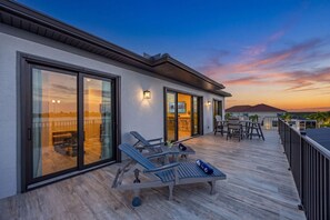 Une terrasse extérieure moderne dotée de portes-fenêtres coulissantes, de chaises longues et d’un espace bar.