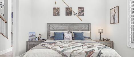 Un dormitorio con cama, mesitas de noche, un reloj de pared y cuadros enmarcados.